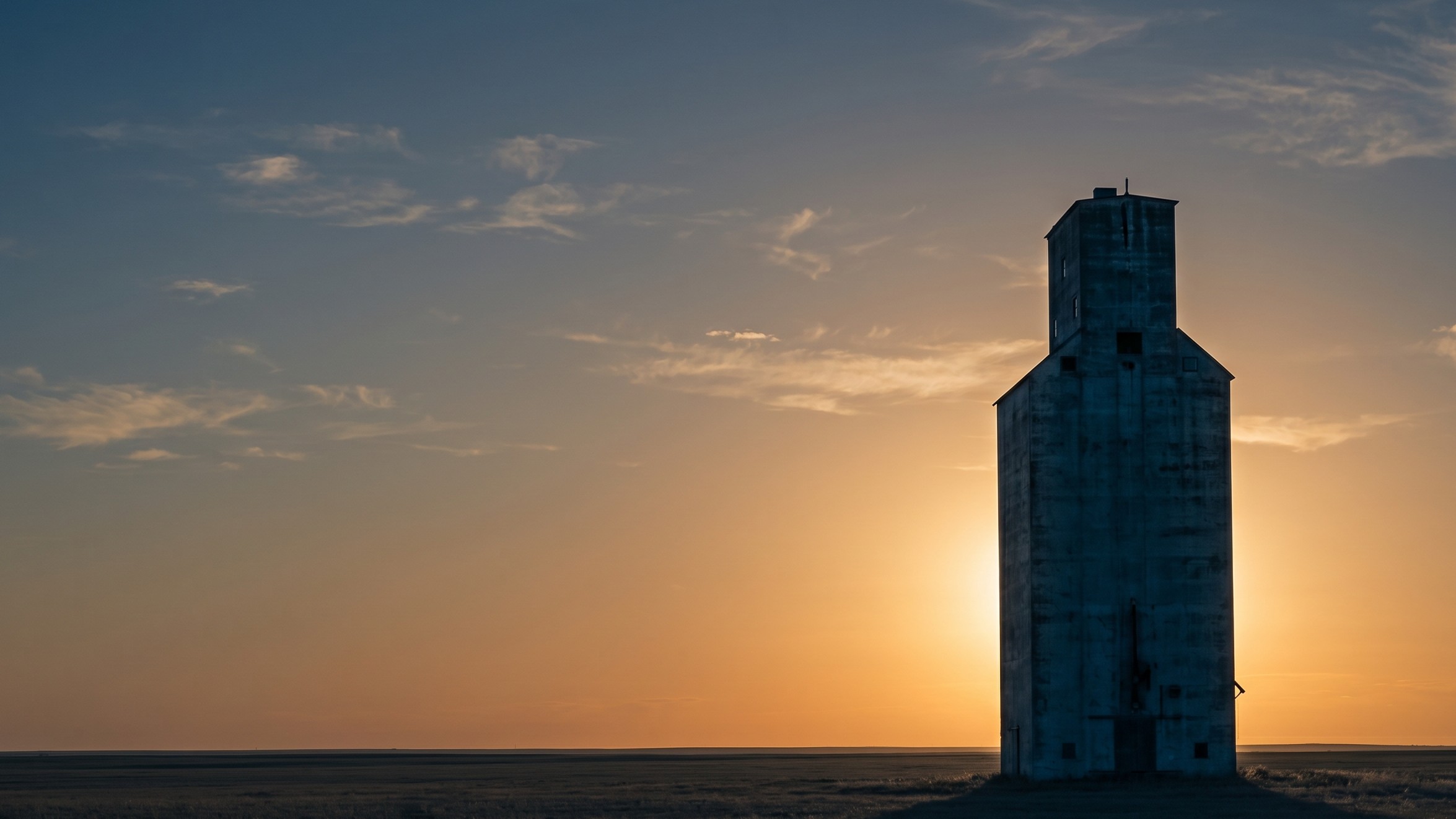 A weathered concrete grain elevator silhouetted against a South Dakota sunset